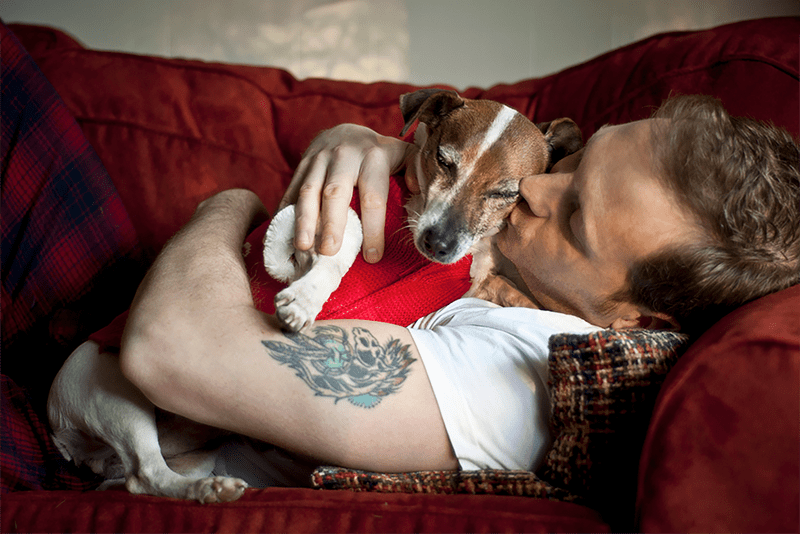 A man laying on the couch with his dog.